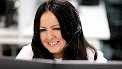female customer service agent wearing headset and smiling at computer