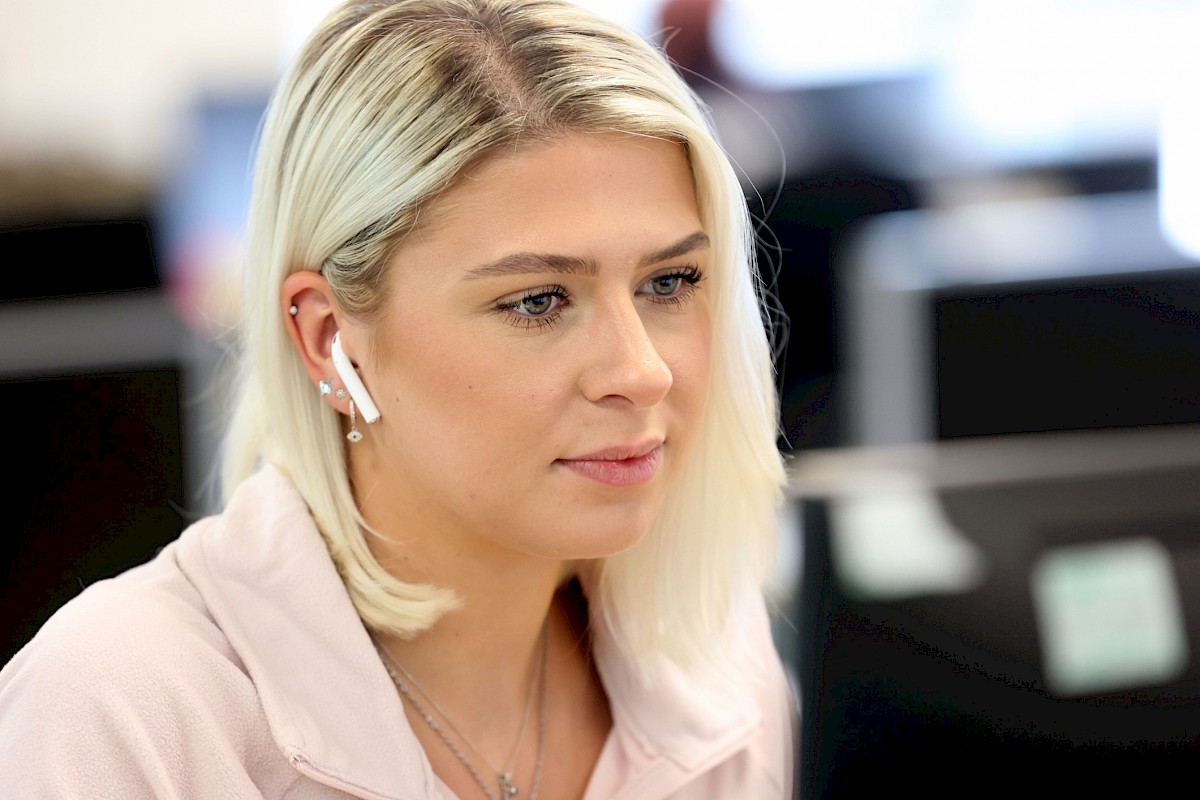 female customer service agent with earpiece looking at laptop screen