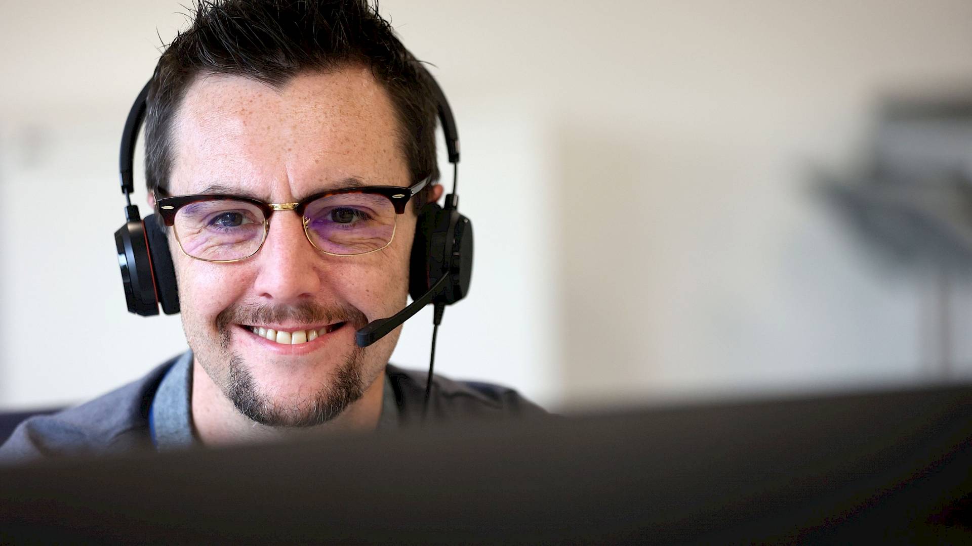 Male customer service agent wearing headset smiling