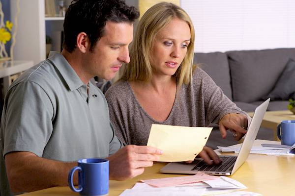 Couple looking at bills in front of laptop