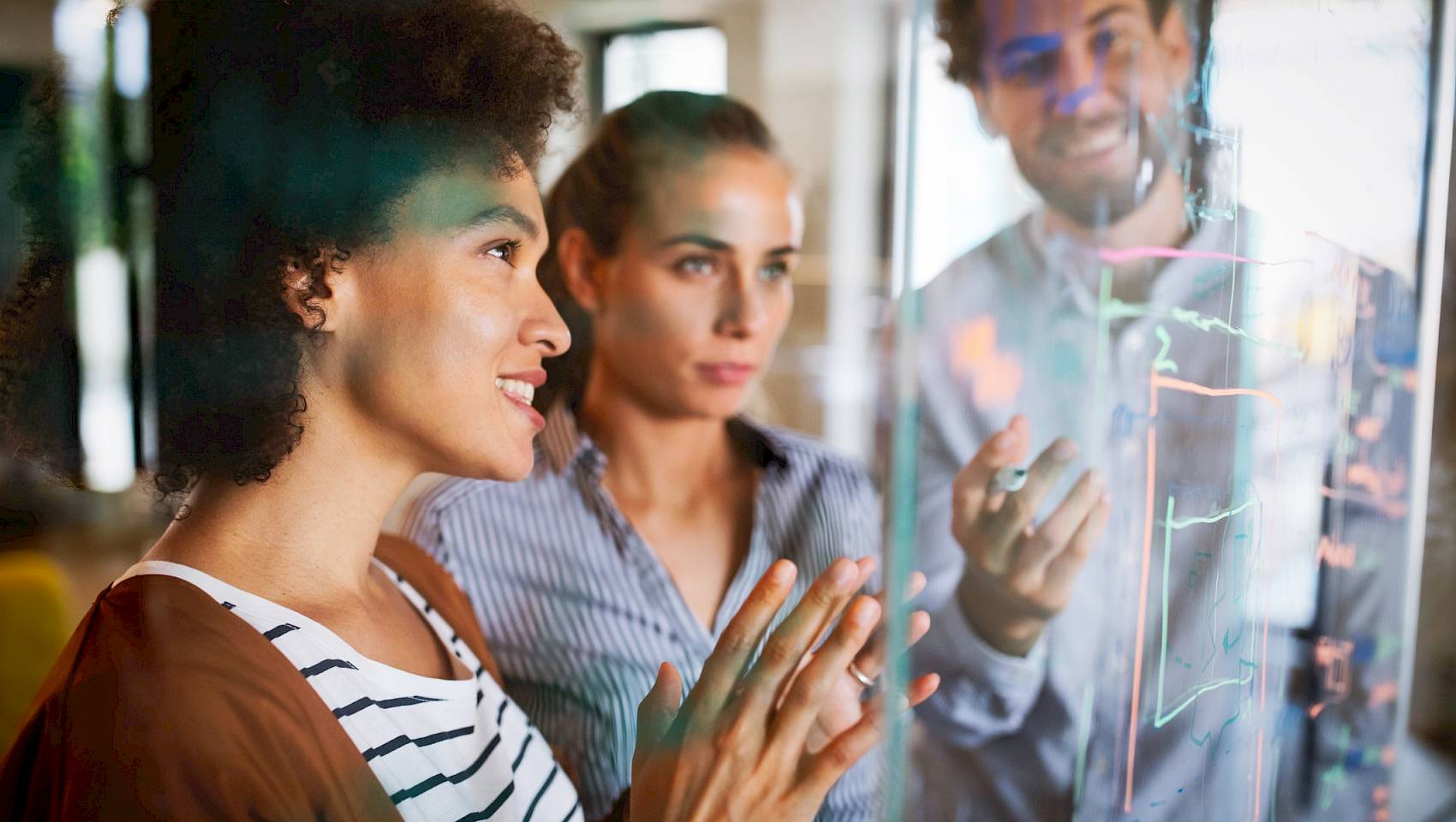 Young professional project management team looking at digital whiteboard