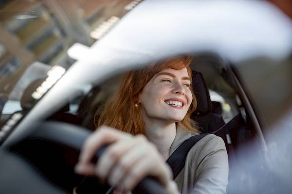Red headed female smiling and driving a car