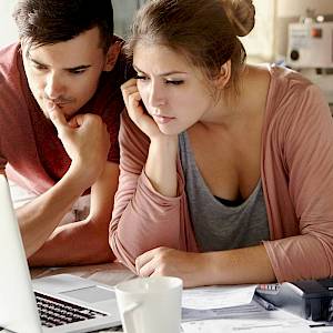 Young couple looking at a laptop screen intently