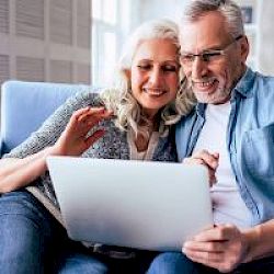 middle aged male and female couple looking at laptop and smiling
