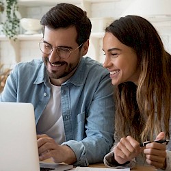 Young male and female couple looking at laptop and smiling