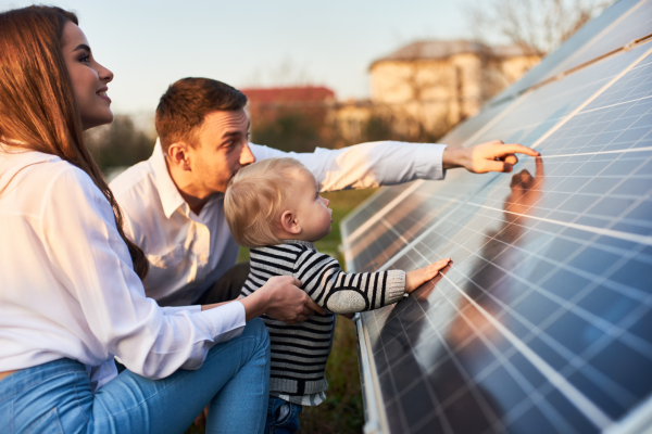 Family with young child leaning on solar panel
