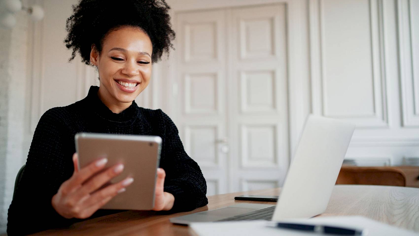 Female and male professional in office sharing laptop smiling
