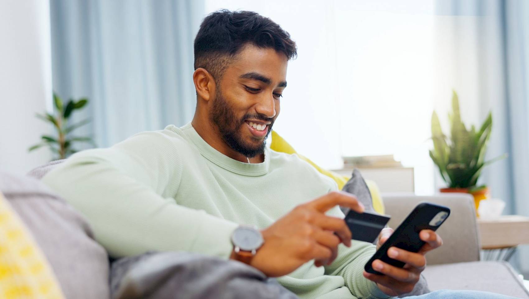 Young male smiling using mobile phone for banking