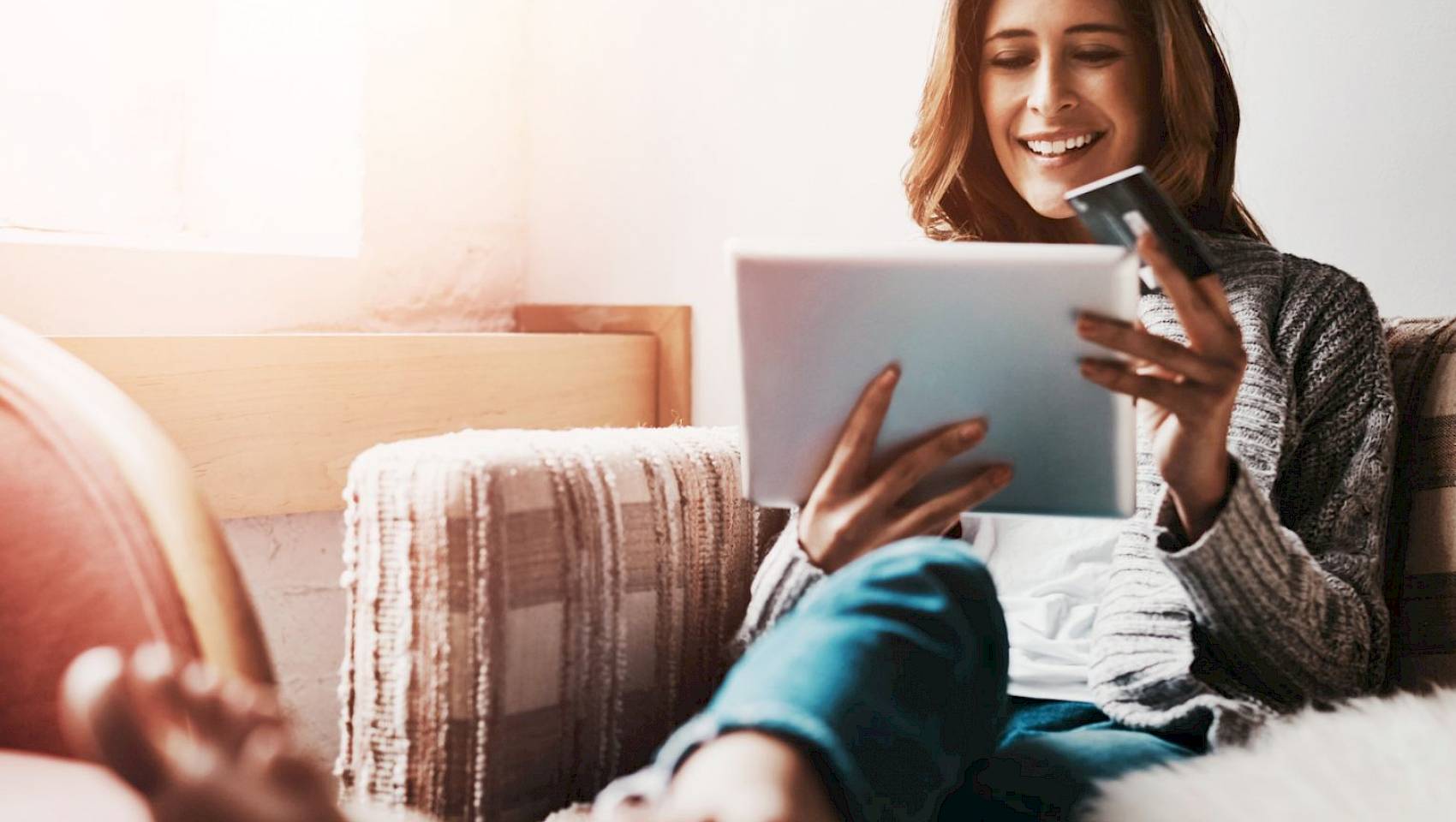female customer on tablet device smiling holding payment card