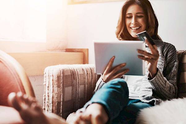 female customer on tablet device smiling holding payment card