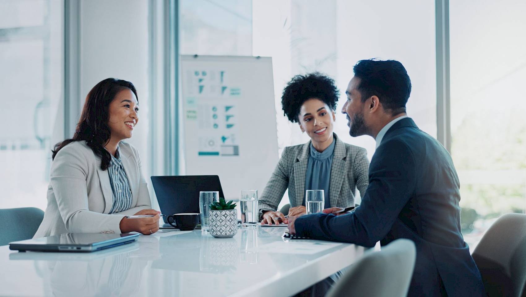professional male and female team looking at laptop screen smiling in office setting