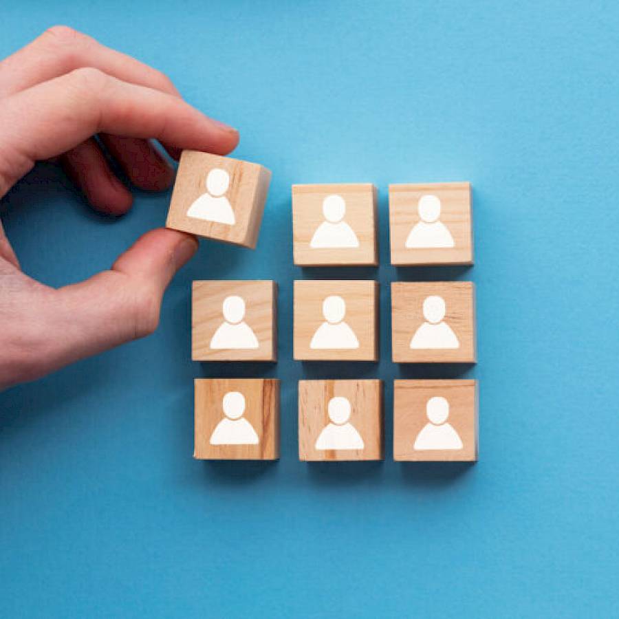 a hand putting a wooden blog with a person icon into a stack