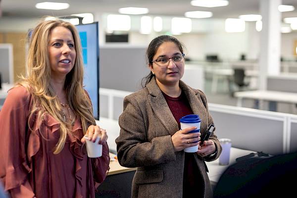 Two female professional coleagues drinking coffee and concentrating