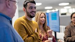 Female professional wearing head set in front of computer and smiling