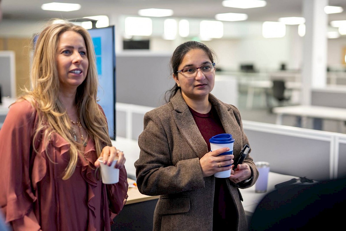 Professional female colleagues smiling and holdeing coffee cups