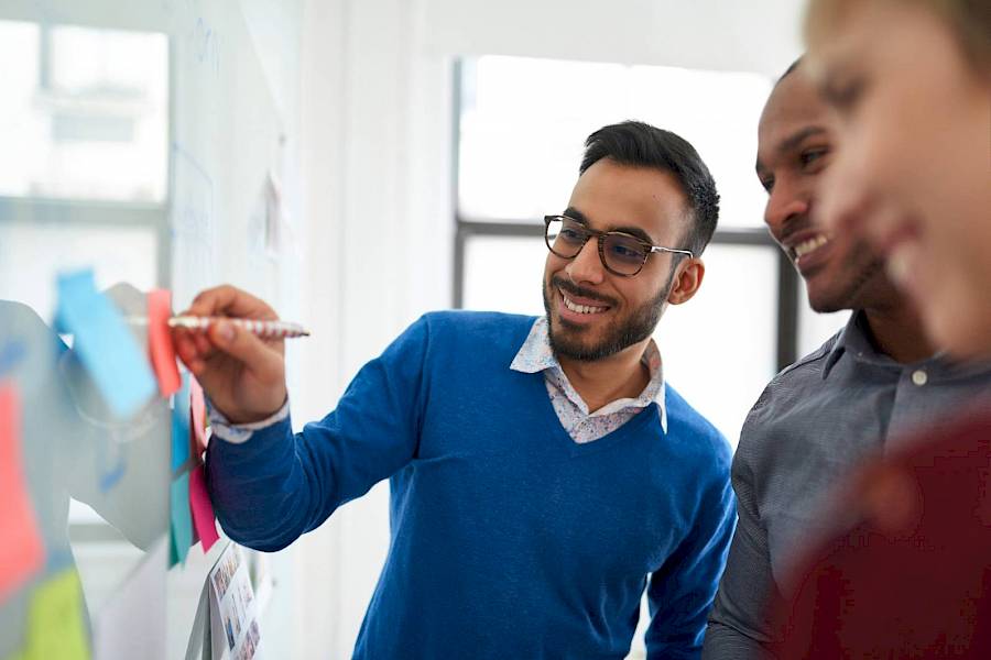 Professional colleagues smiling and planning at whiteboard