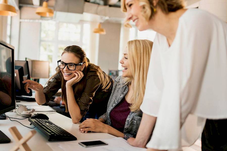 Female professional smiling in meeting looking at large computer screen together