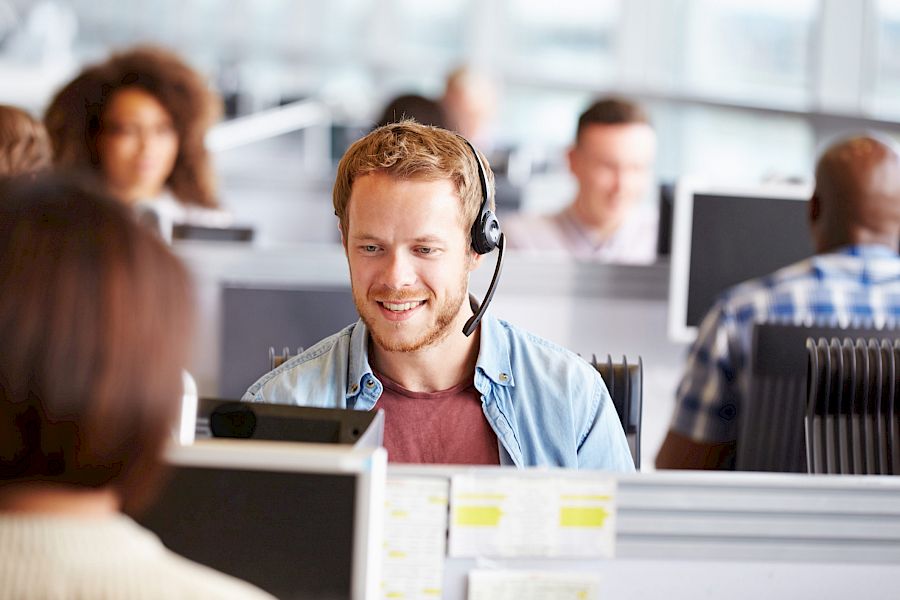 Happy call centre agent with headset helping out a customer