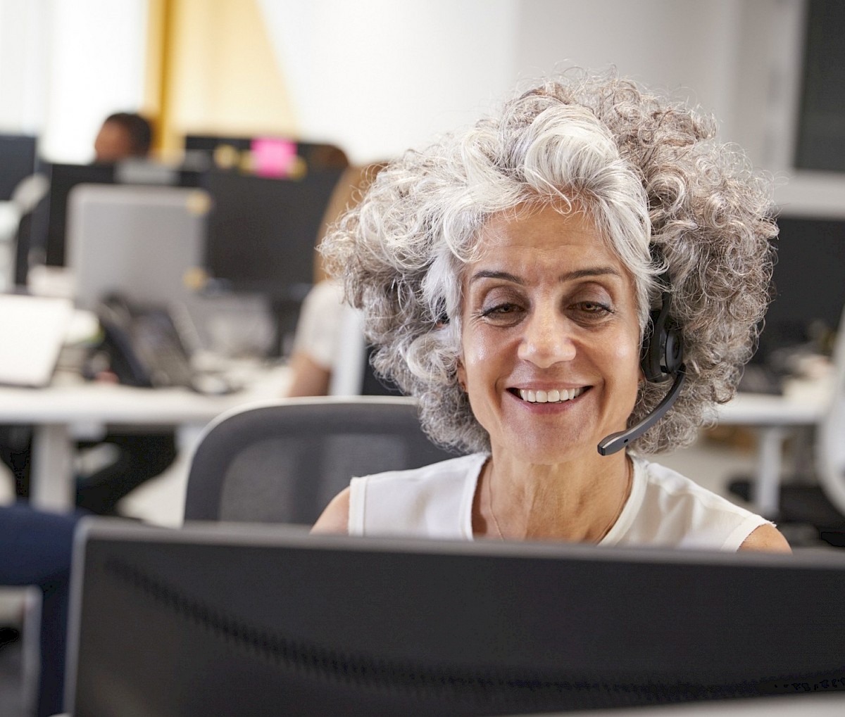 Customer sservice agent, femal, grey hair, smiling.